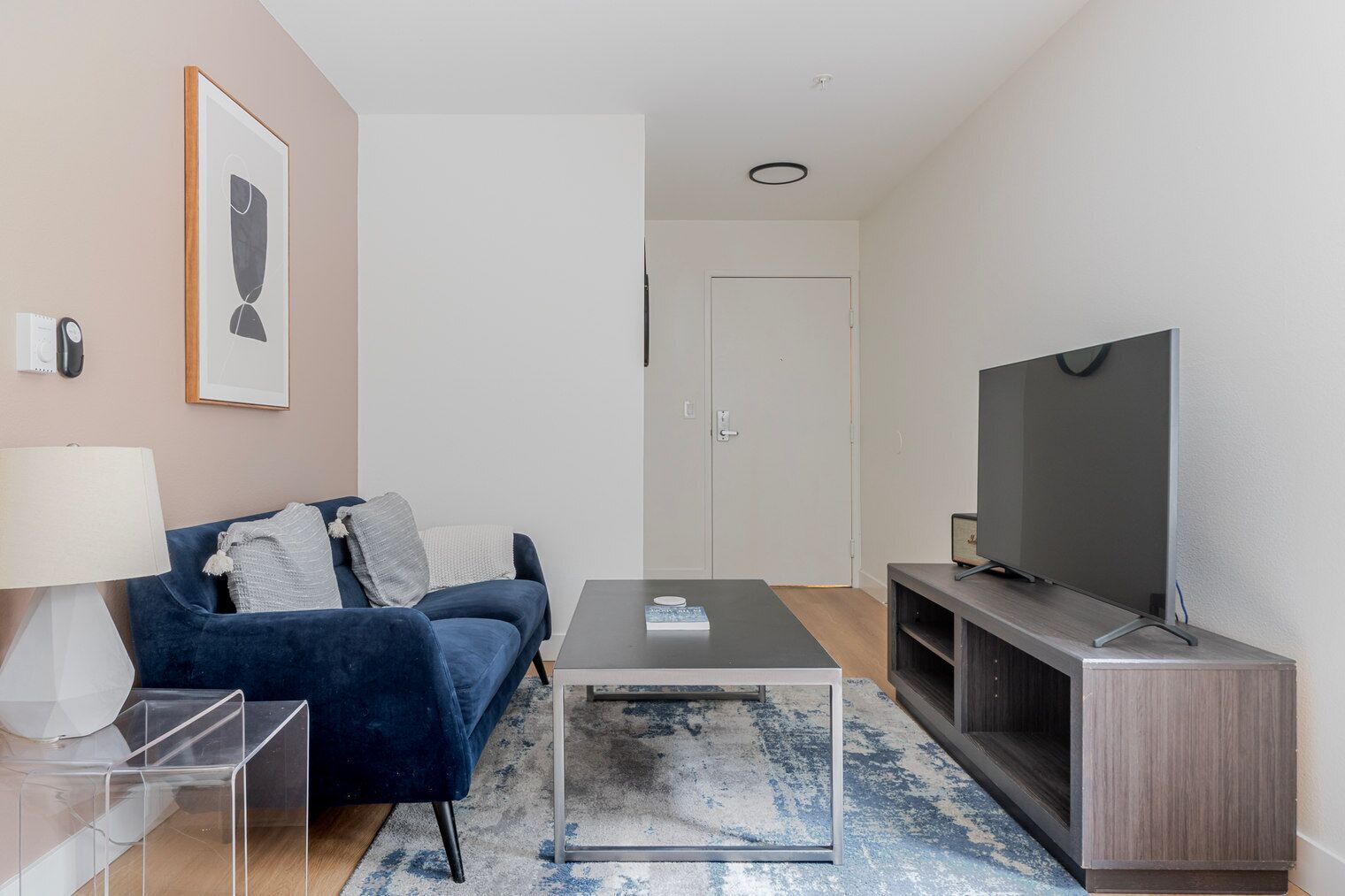 Uma sala de estar moderna com sofá, mesa de centro, TV e um conjunto de escritório clean.