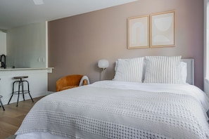 A bedroom with a large bed, a chair, a desk, and a mirror. - Blueground | Denny Triangle, fitness center, nr Seattle Art Museum (Seattle)
