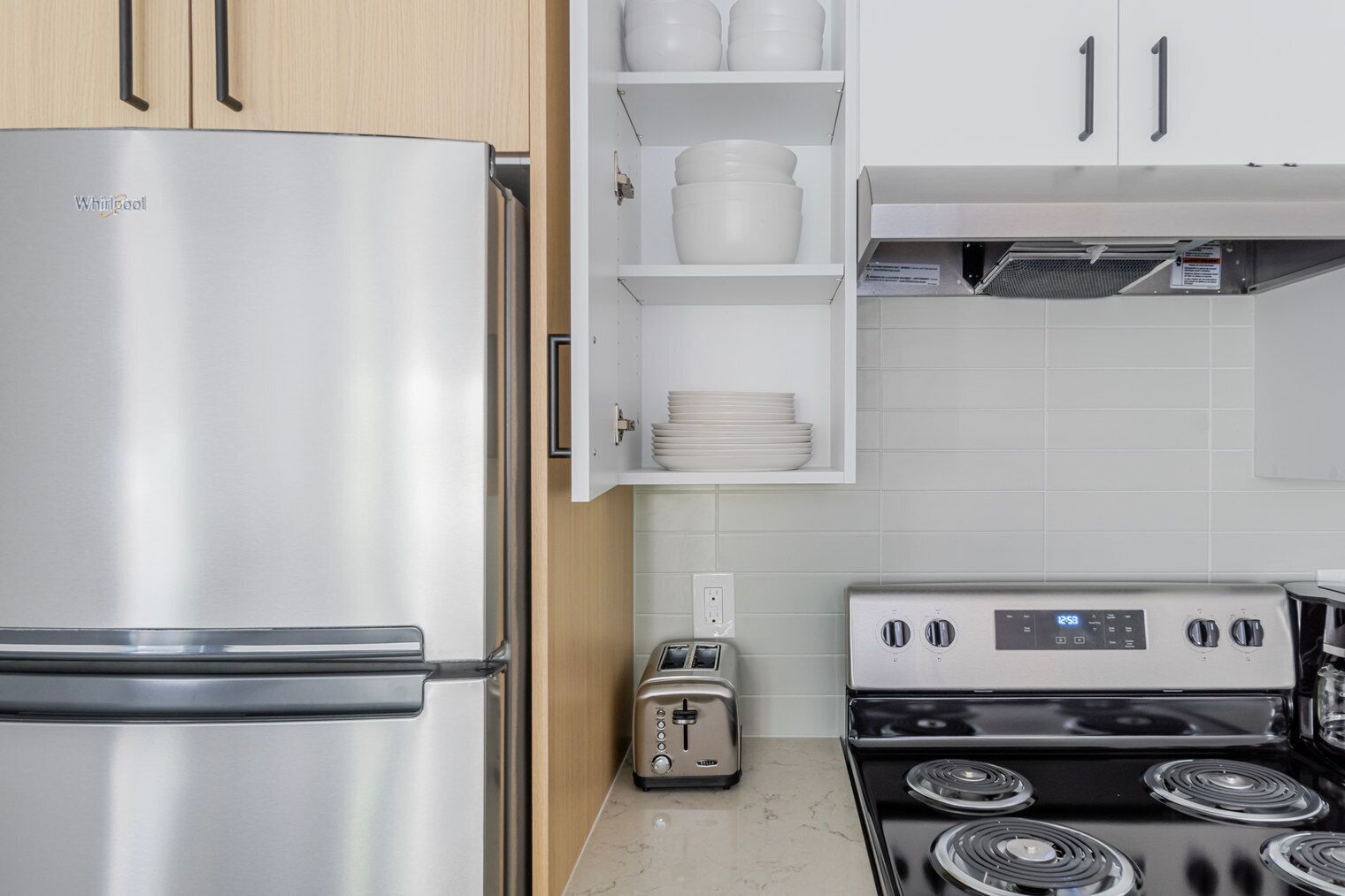A kitchen with a stainless steel refrigerator, a toaster, and a stove.