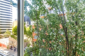 A view through a window of a cityscape with buildings, trees, and a clear sky. - Blueground | Denny Triangle, fitness center, nr Seattle Art Museum (Seattle)