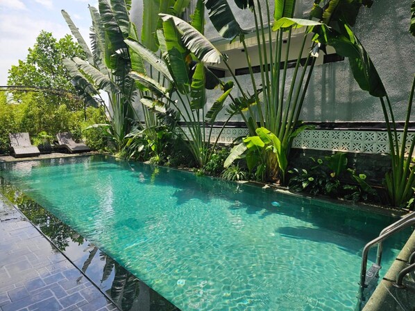 A clear swimming pool with lounge chairs and tropical plants. - Lotus Hotel (Nam Hoa Lu)