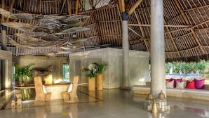 A spacious lobby with a high ceiling, thatched roof, and a seating area with cushions and plants. - Billionaire Resort And Retreat (Malindi)