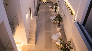 Un espacio arquitectónico moderno con una escalera central, plantas en macetas e iluminación empotrada.