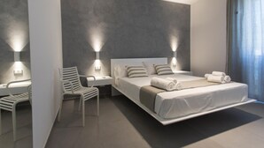Un dormitorio moderno con cama, mesitas de noche, una silla e iluminación montada en la pared.