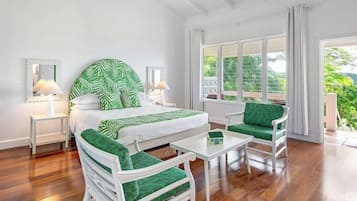 A room with a bed, two chairs, a small table, and a window with curtains.