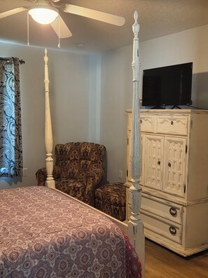 A bedroom with a four-poster bed, a television on a dresser, patterned curtains, and a ceiling fan. - Rest and Relaxation! Home away from home! Pet friendly! Convenient location! (St. Augustine)