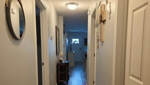 En hall med trägolv, vita väggar och en taklampa.