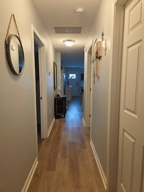 A hallway with wooden flooring, white walls, and a ceiling light. - Rest and Relaxation! Home away from home! Pet friendly! Convenient location! (St. Augustine)