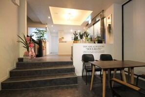 Zona de recepción de un hotel con una escalera, un mostrador de recepción y un área de descanso.