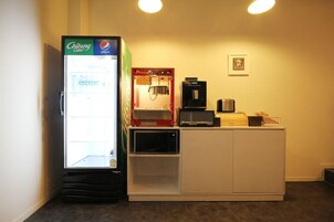 Máquina expendedora con bebidas, máquina de café y microondas.