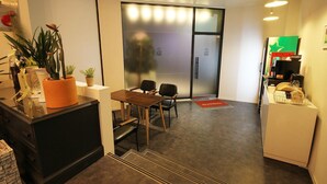 A modern hotel lobby with a reception desk, seating area, and a glass door leading to a room. - Hotel Yam Andong (Andong)