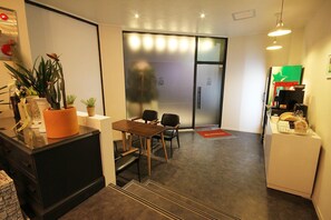 Un moderno vestíbulo de hotel con una recepción, un área de descanso y una puerta de vidrio que da a una habitación.