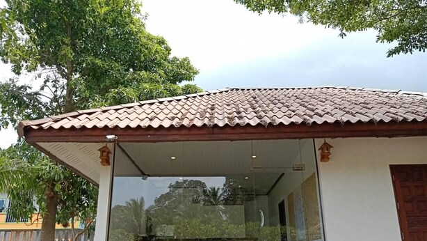 A covered outdoor area with a tiled roof, glass walls, and a wooden door. - Talkoo Eco Resort (Khanom)