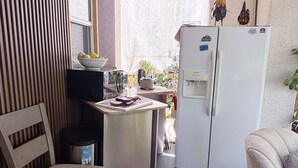 A compact kitchen with a refrigerator, a small dining table, and a chair. - Your cozy getaway awaits in San Diego at this delightful house. (San Diego)