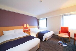 A hotel room with two beds, a small round table, and a single chair. - Juraku Stay Niigata (Niigata)