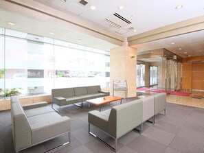 A modern waiting area with seating, a coffee table, and large windows. - Juraku Stay Niigata (Niigata)