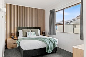 A bedroom with a bed, bedside tables, a window, and a view of the outside. - Cozy Retreat 1 - comfort and convenience with parking (Taupō)