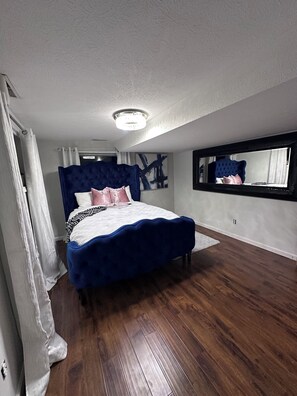 Ein Schlafzimmer mit einem großen Bett, einer Deckenleuchte, einem Fenster mit Aussicht und einem Spiegel an der Wand.