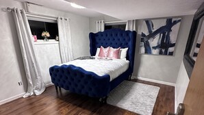 A bedroom with a large bed, wooden flooring, a window with curtains, and a painting on the wall. - Spacious 5-bedroom house for corporate tenants (Columbus)