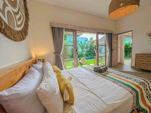 Ein Schlafzimmer mit Bett, Blick auf den Garten und einem hölzernen Schminktisch.