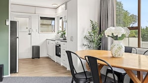 A modern kitchen with white cabinets, a dining table with chairs, and a window with a view. - Cozy Retreat 2 - modern townhouse living (Taupō)
