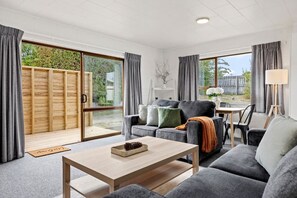 A modern living room with a sofa, coffee table, and a dining area with chairs.