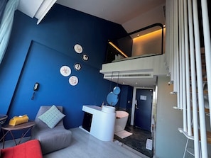 A modern room with a blue accent wall, a sofa, a small table, a white console, and a mirror. - Hayata Hotel No Children Under 12 Years Old (Hengchun)