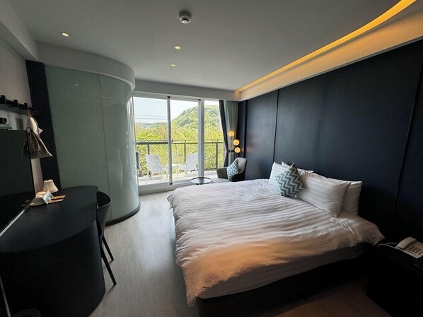 A modern hotel room with a large bed, a desk, and a balcony with chairs. - Hayata Hotel No Children Under 12 Years Old (Hengchun)