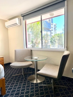 A hotel room with a large window, two chairs, a small round table, and an air conditioning unit on the wall. - Hotel Lea N (Tijuana)