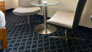 A hotel room with a large window, two chairs, a small round table, and an air conditioning unit on the wall. - Hotel Lea N (Tijuana)