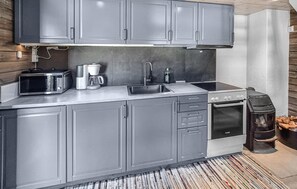 Eine moderne Küche mit grauen Schränken, einer Edelstahl-Spüle, einem Backofen von Bosch und einer Kaffeemaschine.