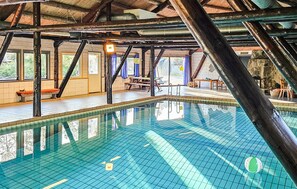 An indoor swimming pool with clear water, wooden beams, and a bench area. - Gorgeous home in Tjørhom with sauna (Tjørhom)