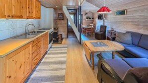 A compact kitchen with wooden cabinets, a sink, and a stove. There's a dining area with a table and chairs, and a sofa. - Gorgeous home in Tjørhom with sauna (Tjørhom)