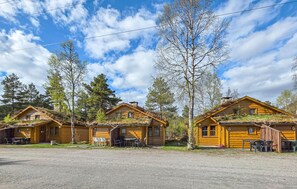 A row of log cabins with outdoor seating, surrounded by trees. - Cozy home in Tjørhom with sauna (Tjørhom)