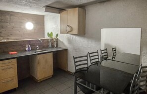A compact kitchen with a sink, cabinets, and a dining area with chairs.