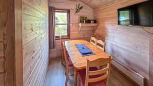 En inredning med träpanel, ett matbord, stolar, en tv och ett fönster.