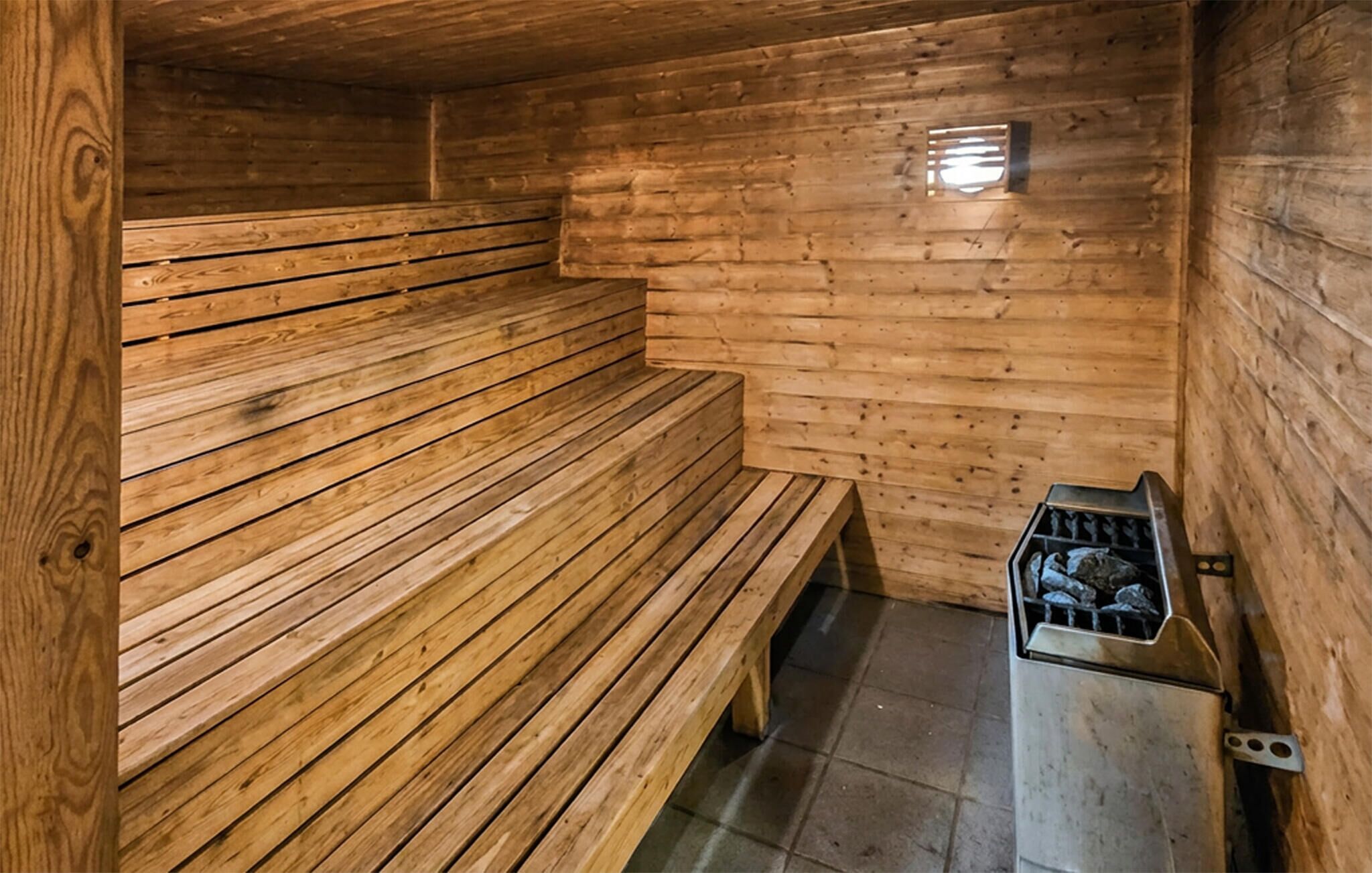 Un sauna avec des bancs en bois et un appareil de chauffage en métal.