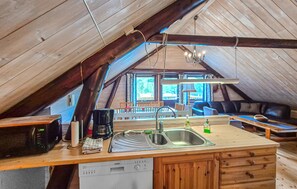 A cozy attic kitchen with a wooden island, a Siemens dishwasher, and a dining area with a couch and chairs.