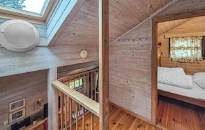A wooden cabin interior with a loft bedroom, a staircase, and a skylight. - Cozy home in Tjørhom with sauna (Tjørhom)