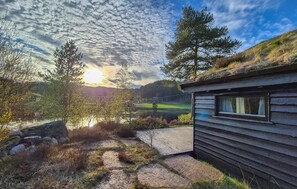 A cabin with a window, surrounded by trees and a path leading to a body of water. - Beautiful home in Tjørhom with sauna (Tjørhom)