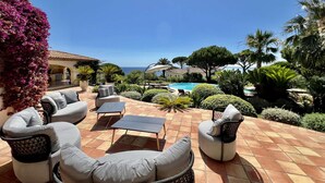 Een terras met tuinmeubilair, een zwembad en uitzicht op zee.