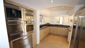 Een moderne keuken met roestvrijstalen apparatuur, houten kastjes en een gebogen plafond.
