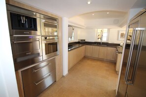 A modern kitchen with stainless steel appliances, wooden cabinets, and a curved ceiling. - MAGNIFICENT VILLA WITH POOL AND SEA VIEW (STE MAXIME)