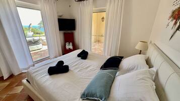 Une chambre d’hôtel comprenant un lit, une télévision, un balcon avec vue et un espace douche.