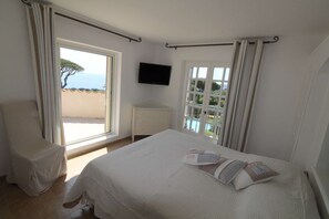 A bedroom with a bed, a chair, a TV, and a window with curtains. - MAGNIFICENT VILLA WITH POOL AND SEA VIEW (STE MAXIME)