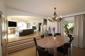 A spacious living area with a dining table, chairs, a chandelier, and a fireplace. - MAGNIFICENT VILLA WITH POOL AND SEA VIEW (STE MAXIME)