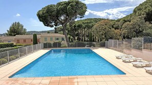 A rectangular swimming pool with a tiled deck, surrounded by a white metal fence, and set against a backdrop of trees and buildings. - Apartment T4 Duplex - 6 people - Sea view - Swimming pool residence - Air conditioning - WiFi -... (STE MAXIME)