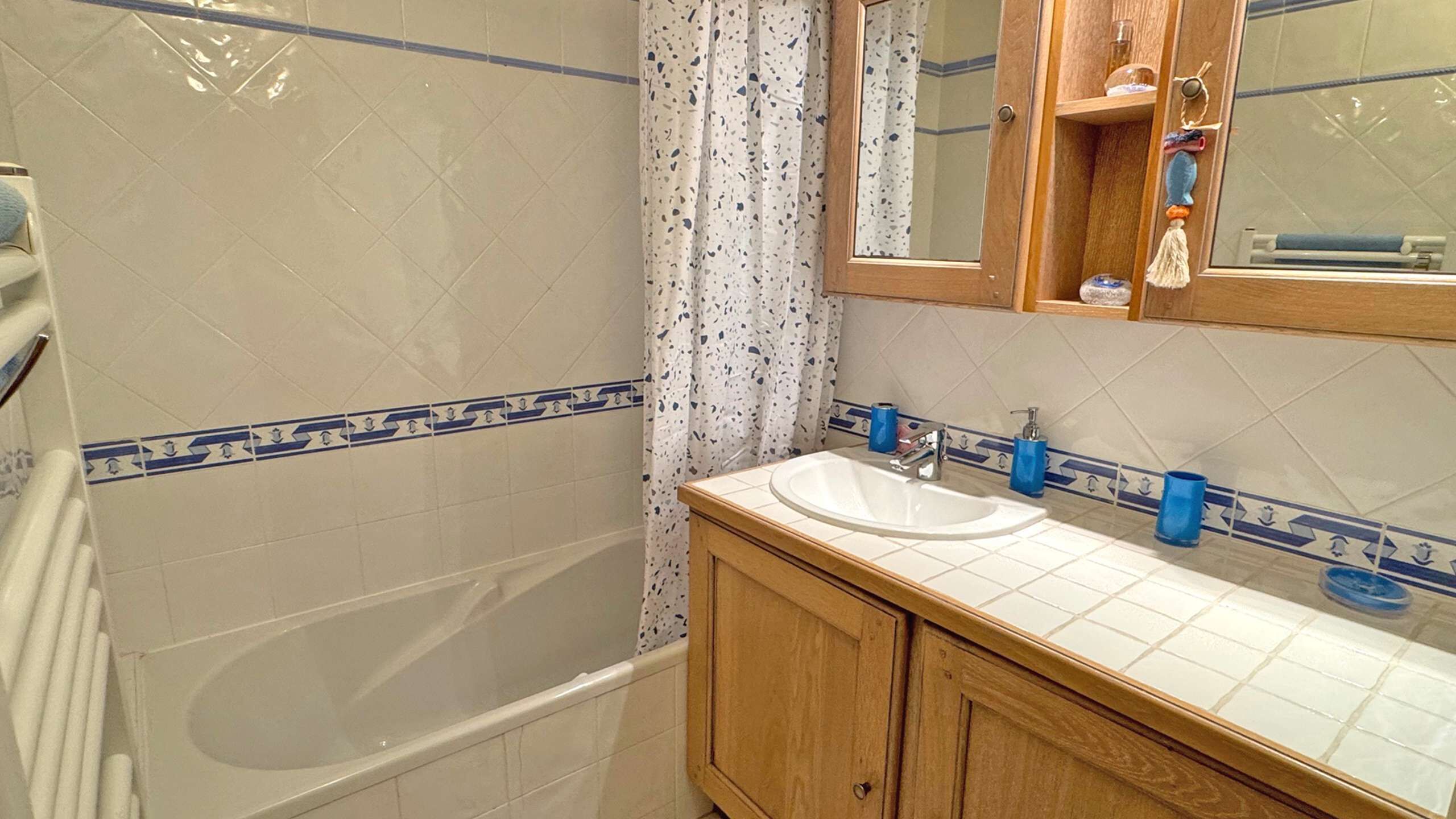 A bathroom with a bathtub, a sink with a mirror above it, and a shower curtain.