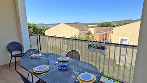 A balcony with a table set for four, chairs, and a view of buildings and hills. - Apartment T4 Duplex - 6 people - Sea view - Swimming pool residence - Air conditioning - WiFi -... (STE MAXIME)