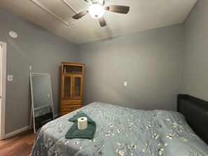 Une chambre à coucher comprenant un lit, un ventilateur de plafond, une armoire et un miroir.